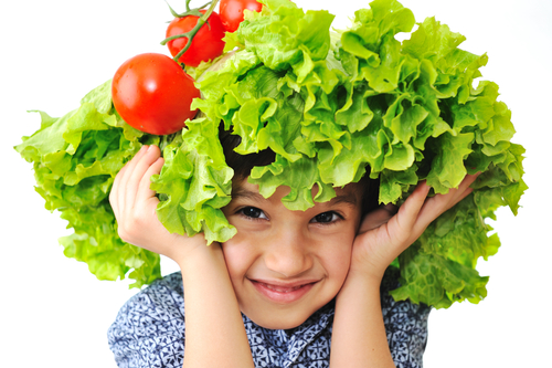 child using lettuce and tomatos as a hat